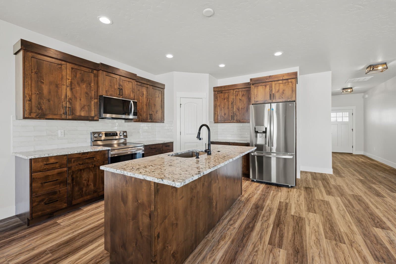 Kitchen with dark wood cabinets, granite island, and white subway tile in an Old's Ferry home