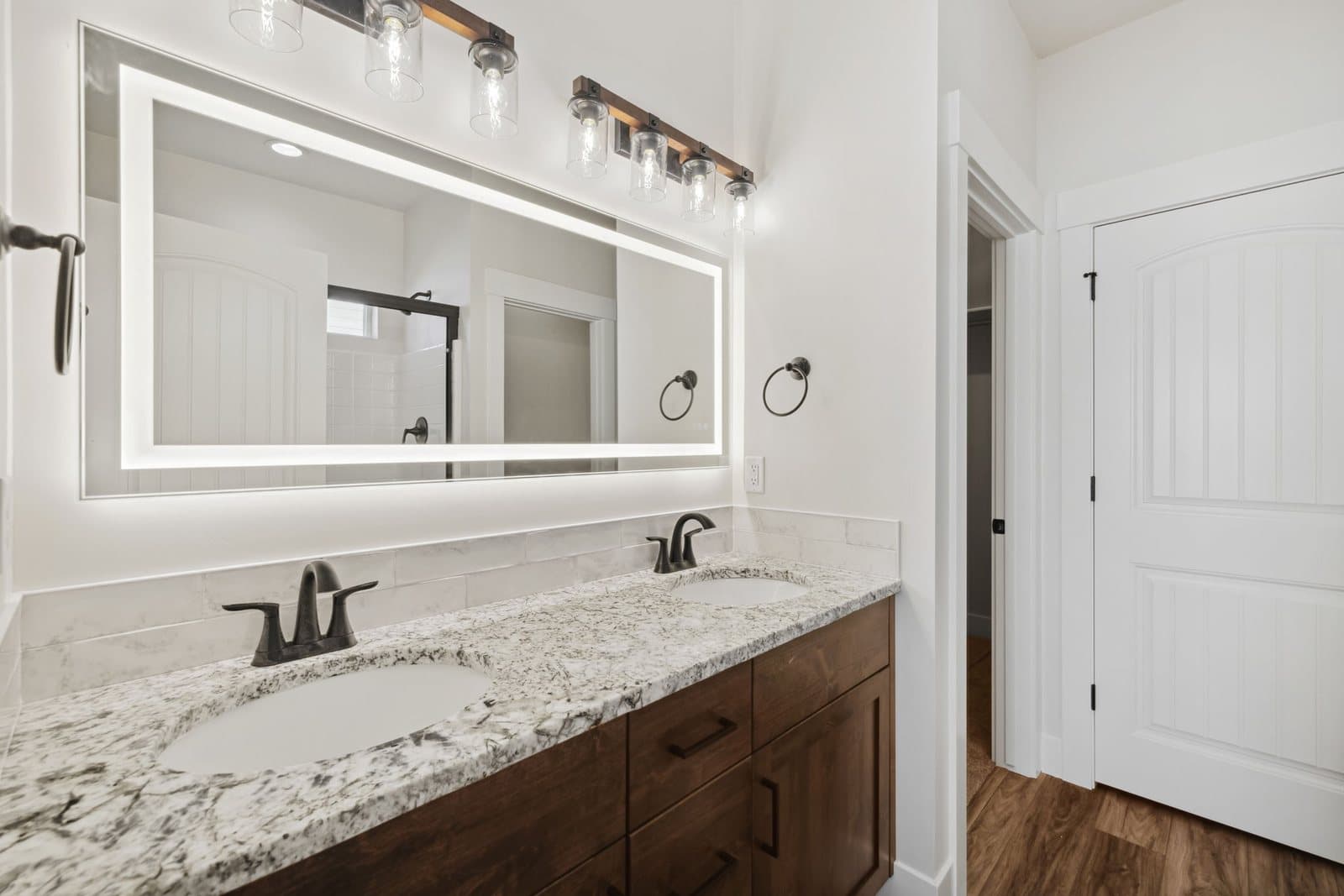 Primary bathroom with double vanity and lighted mirror in an Old's Ferry home