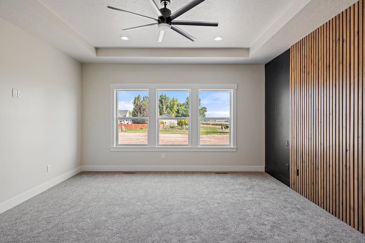 Bedroom with a wood slat accent wall and picture windows at 16966 Long Meadow Dr